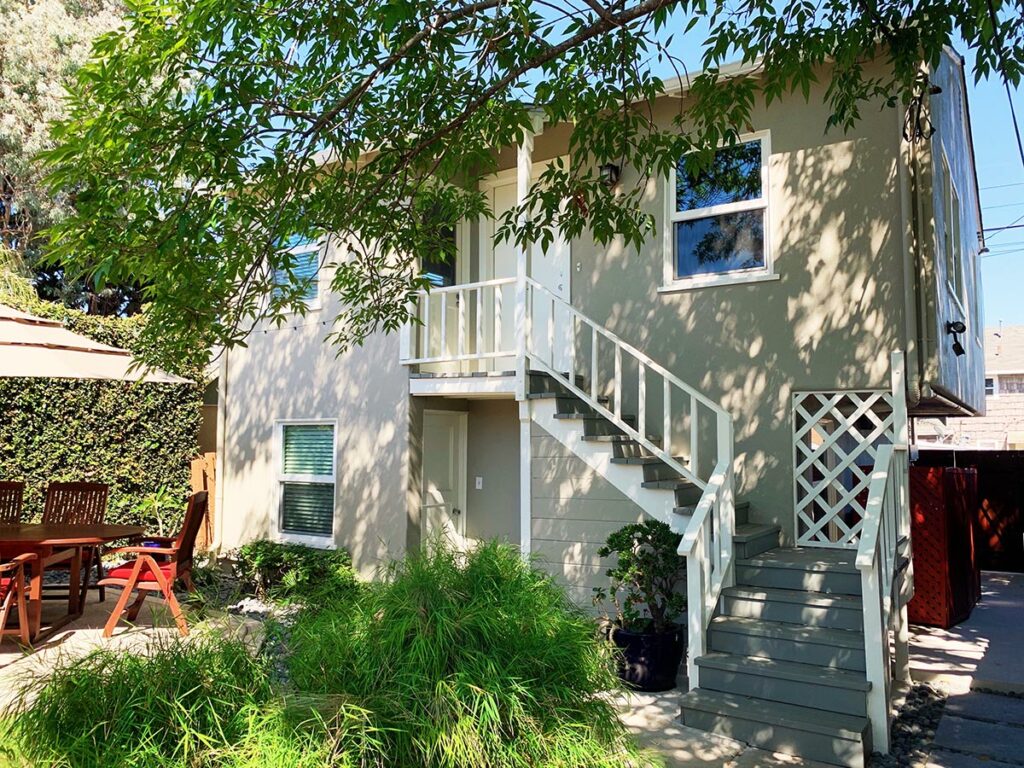 Exterior sitting area with umbrella and stairs leading up to bed and breakfast.