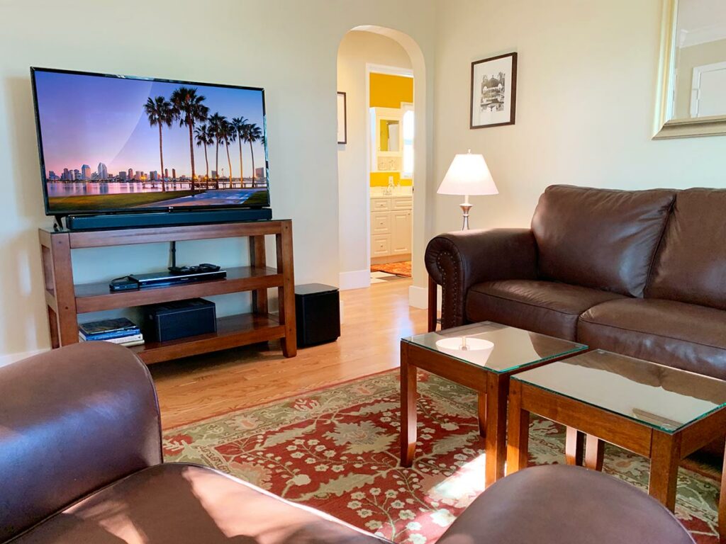 Separate living room with leather couch and love seat, flat screen TV in this roomy bed and breakfast.