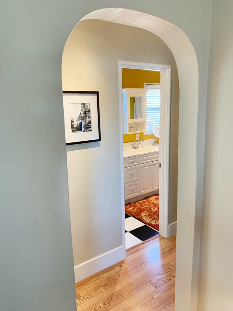 Arched doorway in bed and breakfast looking into hallway and bathroom.